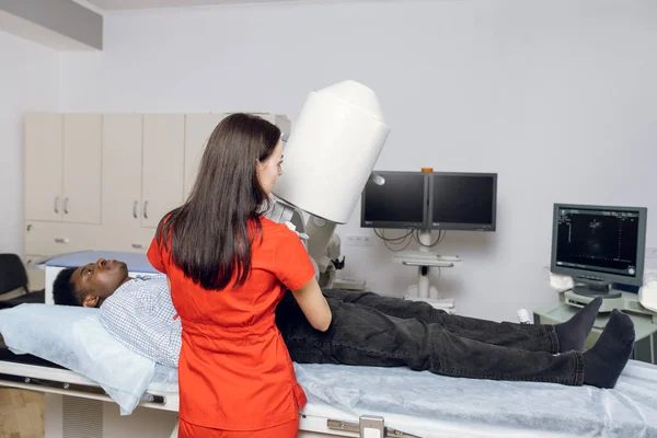Lithotripsy for kidney and ureteral stones. Back view of woman doctor, using ultrasound scan to determine the stone position before the lithotripsy. Modern lithotripter to break up kidney stones — Stock Photo, Image