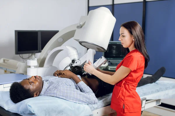 İdrar yolu taşlarının invazif olmayan ekstrakporeal şok dalgası litotripsi ile tedavi edilmesi. Erkek hastasına taş kırmak için modern lithotripter ile çalışan profesyonel bir kadın doktor.