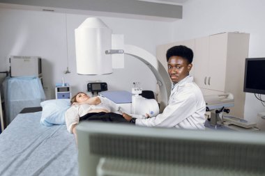 Modern merkezde böbrek ve idrar taşları için litotripsi. Profesyonel Afrikalı doktor, kadın hastasının taş pozisyonunu belirlemek için ultrason taraması yapıyor.
