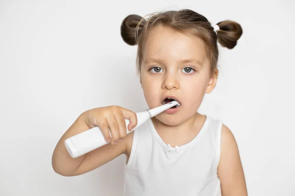 El concepto de cuidado diario e higiene de la cavidad bucal, prevención de la caries dental. Adorable niña de 3 años por la mañana limpia los dientes con un moderno cepillo de dientes eléctrico. — Foto de Stock