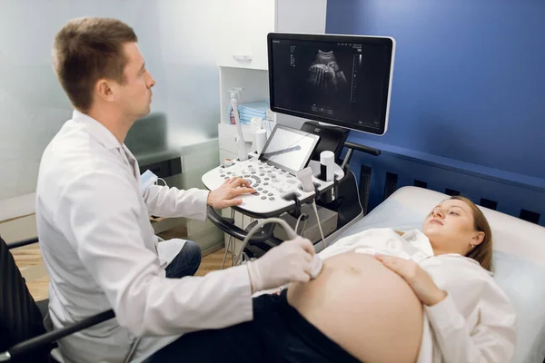 Maternidade saudável, medicina e conceito de ultra-som. Jovem grávida visitando seu médico masculino na maternidade, fazendo ultra-som, preocupado com a saúde da criança — Fotografia de Stock