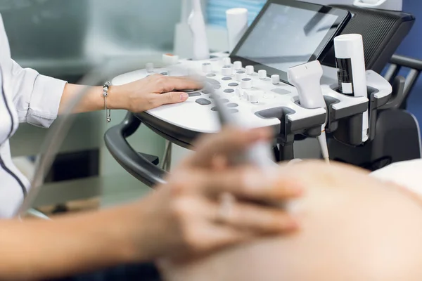 Close up imagem recortada de médico obstetra do sexo feminino, pressionando botões em um painel de controle que executa o procedimento de ultra-sonografia para mulher grávida — Fotografia de Stock