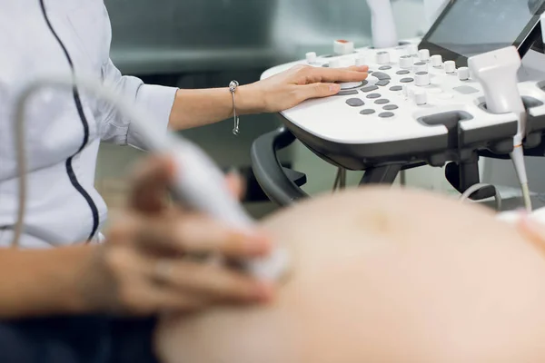 Imagen de cerca recortada del obstetra médico femenino, pulsando botones en un panel de control que realiza un procedimiento de ecografía para la mujer embarazada —  Fotos de Stock