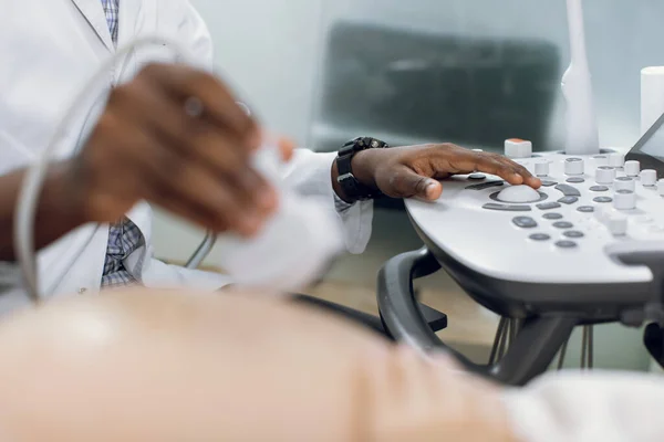 Cuidados de saúde, conceito de ultra-som. Close up tiro recortado de mãos de médico africano masculino, triagem de mulher grávida por ultra-som, pressionando botões no painel de controle. Concentre-se na mão nos botões — Fotografia de Stock