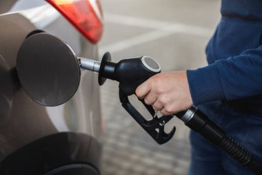 Benzin istasyonunda benzini dolduran adamların yakınına. Bir motorlu taşıt arabasına benzin dolduruluyor..