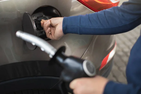 Close up immagine ritagliata di mani maschili, tenendo pistola di riempimento, e l'apertura del serbatoio di carburante della sua auto di lusso, pronto per il rifornimento dell'auto al distributore di benzina — Foto Stock