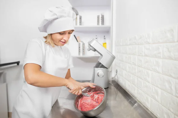 Bella giovane donna, pasticciera professionista, che prepara panna rossa o pastella in ciotola di acciaio inossidabile, mescolandola con spatola. Cuocere in cucina, facendo la crema per torta o maccheroni — Foto Stock