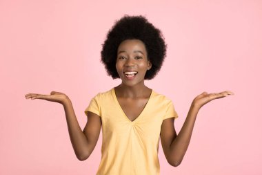 Hangisinin daha iyi, hangisini seçeceğini. Genç, mutlu, afro saçlı Afrikalı bir kadın. Pembe arka planda elleriyle iki seçenek sunuyor.