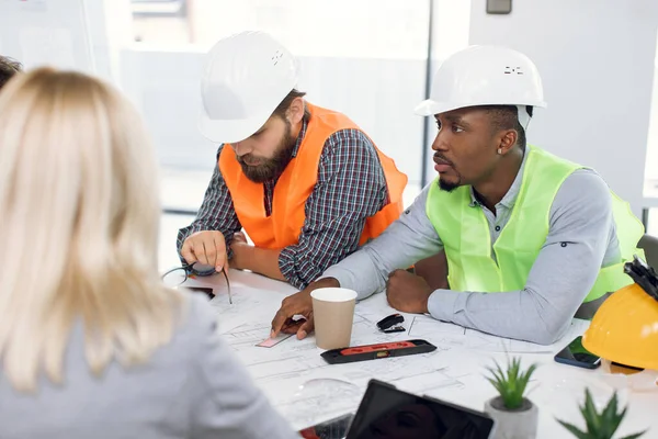 Multiraciale kontorarbejdere, der har møde om byggeri - Stock-foto