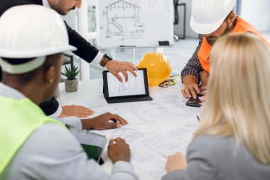 İşçiler inşaat planı yapmak için aygıt kullanıyorlar