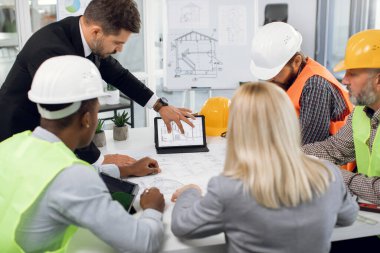 İnşaat projesi üzerine beyin fırtınası yapan çok ırklı mühendis ve yöneticilerden oluşan profesyonel bir ekip.