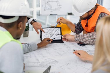 Tabletin planlarını analiz eden inşaat ekibini kapat.