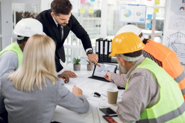Mühendisler ve kadın ve erkek yöneticilerden oluşan çok ırklı bir ekip, ortak inşaat projesi üzerine beyin fırtınası yapıyorlar.
