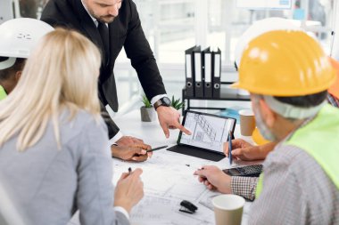 Tabletin planlarını analiz eden inşaat ekibini kapat.