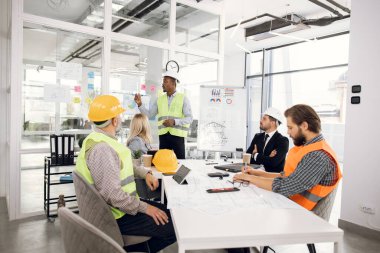 Afrikalı adam inşaat projesini meslektaşlarına sunuyor