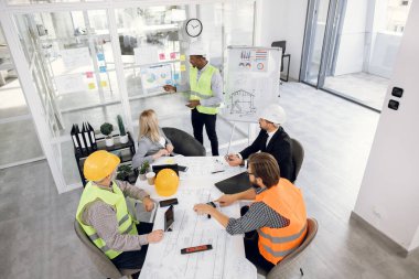 Ofiste inşaat planını inceleyen beş farklı işçi.