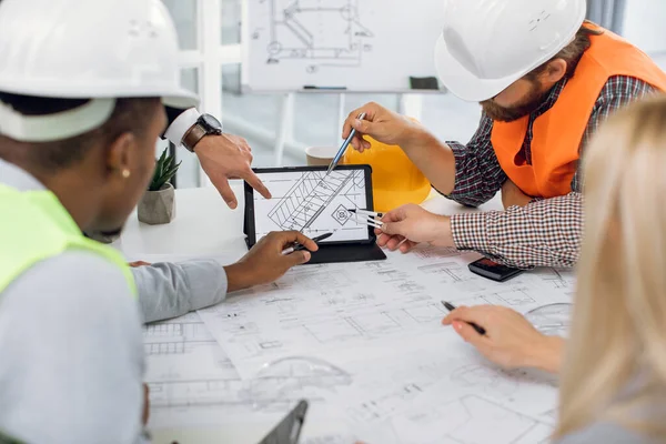 Close up of construction team analysing blueprints on tablet