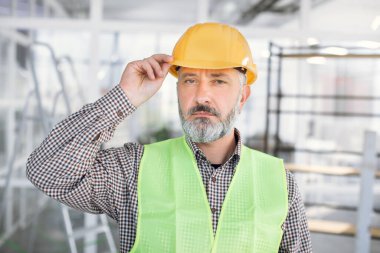 Miğferli olgun mimarın portresi içeride poz veriyor.