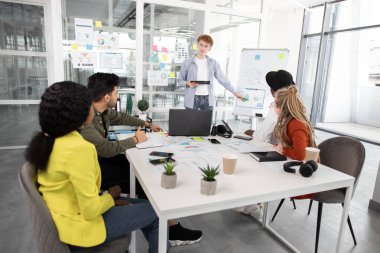 Modern ofisteki çok ırklı genç yaratıcı adam konuşmacısını dinliyoruz.