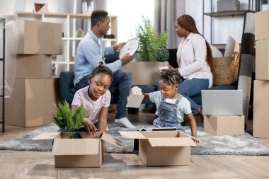 Ebeveynler yeni dairede kutuları açarken çocuklar oyun oynuyor