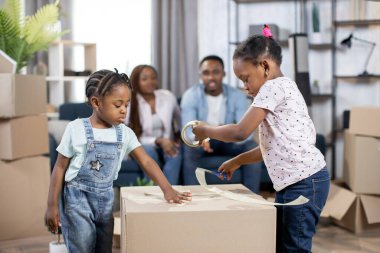 Ebeveynler dinlenirken iki tatlı Afrikalı çocuk kutu paketliyor.