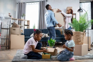 Çocuklar yerde oynarken Afro çift kutuları topluyor