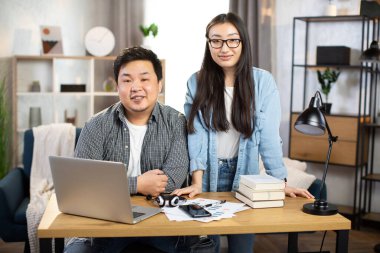 İş yerinde modern aletler kullanan pozitif Asyalı iş arkadaşları