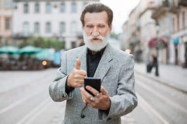 Görüntülü sohbet için akıllı telefonu kullanan mutlu olgun bir adam.