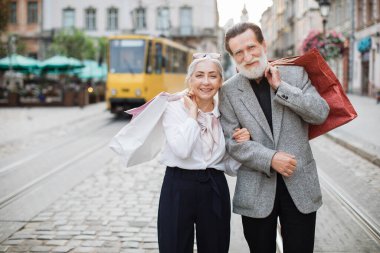 Gülümseyen yaşlı çift alışveriş yaptıktan sonra sokakta poz veriyor.