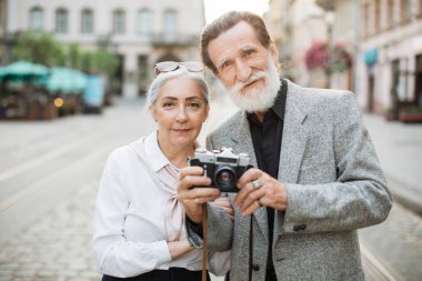 Olgun çift dışarıda eski fotoğraf makinesiyle poz veriyor.