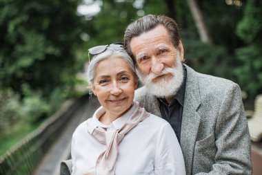 Beyaz, yaşlı bir çift parkta yürüyor.