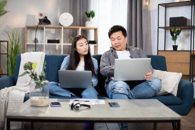 Genç Asyalı öğrenciler evde çalışmak için dizüstü bilgisayar kullanıyorlar.