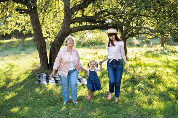 Family joint moments, happy relationship between different generations. Portrait of female multigeneration family, walking outside in the summer sunny garden and having fun