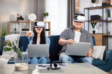 Oyun oynamak için VR kulaklık ve dizüstü bilgisayar kullanan Asyalı çift