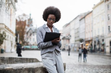 Odaklanmış Afrikalı kadın, şehir sokağında panosuyla oturuyor.