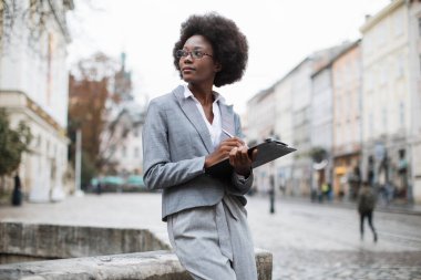 Afro-Amerikalı iş kadını dışarıda panoya yazı yazıyor.