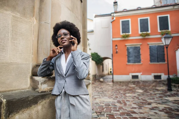 African woman in business suit talking on mobile on street