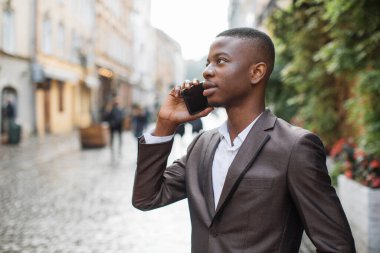 Kendine güvenen afro iş adamı cep telefonuyla konuşuyor.