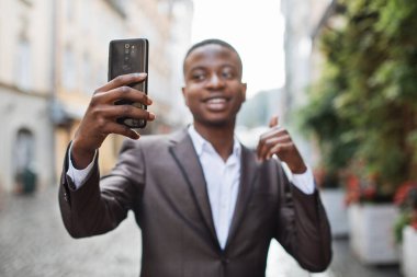 Mutlu afro işadamı akıllı telefonu görüntülü sohbet için kullanıyor