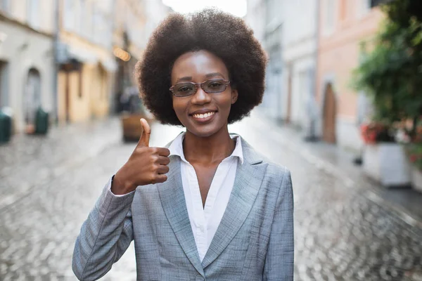 Glimlachende Afrikaanse vrouw in pak tonen duim omhoog buiten — Stockfoto