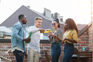 Çok ırklı arkadaşlar çatıda parti veriyorlar.