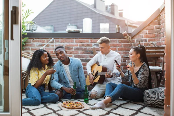 Amis multiraciaux jouer de la guitare, boire et manger — Photo