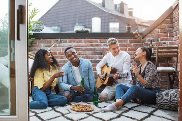 Amis multiraciaux jouer de la guitare, boire et manger — Photo