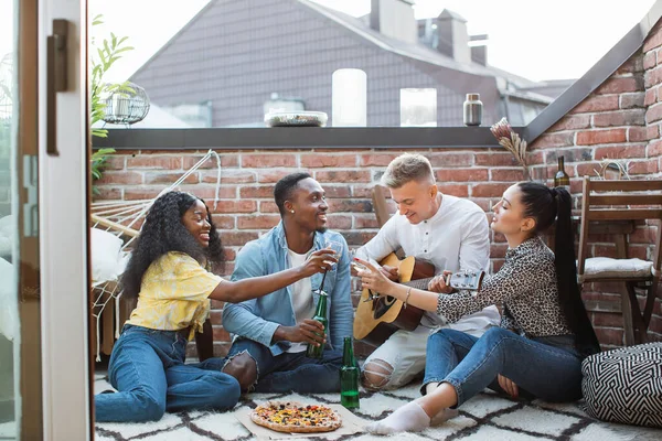 Divers amis faisant la fête avec guitare, boissons et pizza — Photo