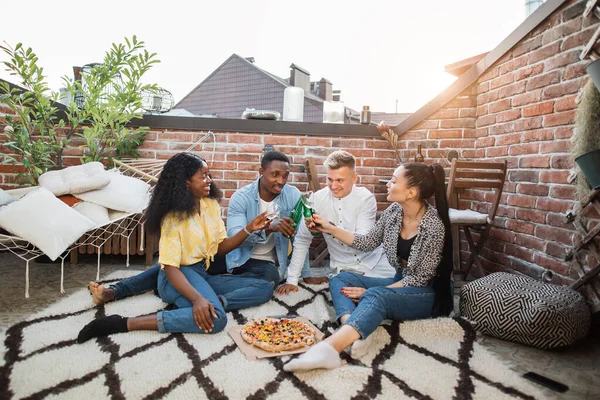 Quatre amis dégustant des pizzas et des boissons alcoolisées à la fête — Photo
