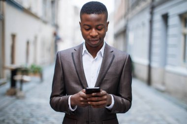 Sokakta akıllı telefon kullanan Afrikalı işadamı