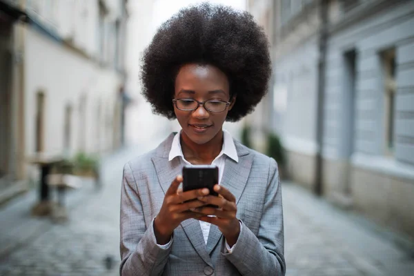 Africano business signora utilizzando smartphone su strada — Foto Stock