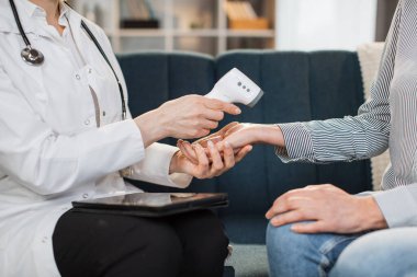 Kızılötesi bilek termometresiyle vücut ısısı ölçümü. Üst düzey hastasının vücut ısısını ölçen kadın doktoru lazer kızılötesi termometre kullanarak yakın plan çekimleri.