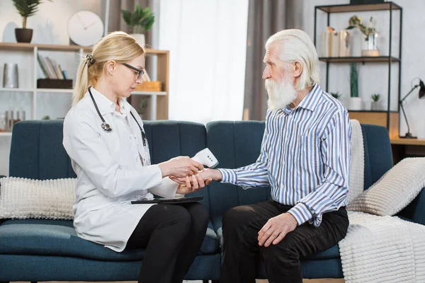 Orta yaşlı pratisyen hasta yaşlı bir adamı evinde ziyaret ediyor. Sarışın bir kadın doktor, evde hasta sıcaklığını ölçüyor ve el değmemiş bilek kızılötesi termometre kullanıyor..