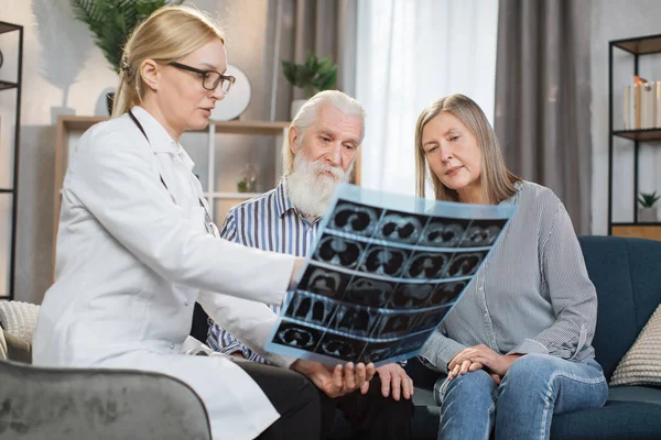 年轻貌美的一对老年夫妇满意的画像，看了X光扫描，听了专业自信的女医生的意见，在家里拜访了她们，谈论了肺部情况. — 图库照片